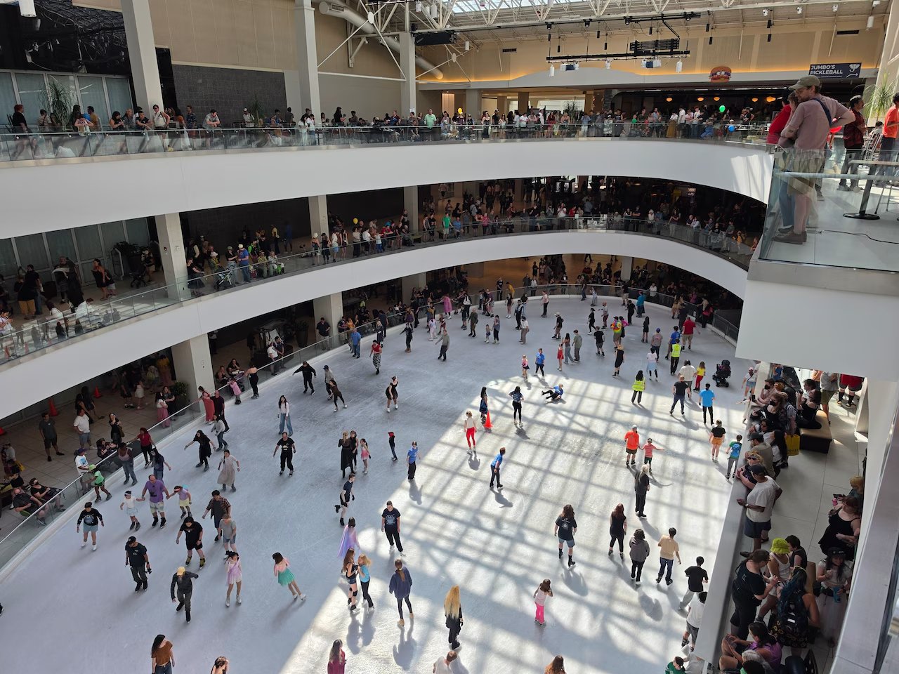 Dozens of skaters on the rink, seen from above, with people lined along the balconies. Photograph published by The Oregonian.
